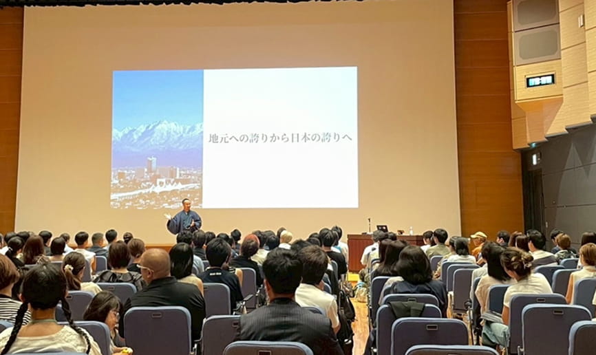 多くの参加者が集まるホールで小倉瑞季が講演を行っている様子