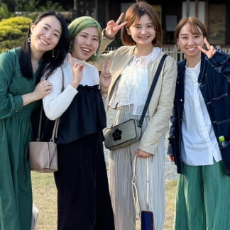 屋外で笑顔の4人が並んで撮影している写真