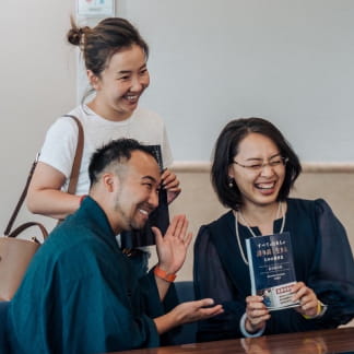 室内で談笑しながら本を持っている写真