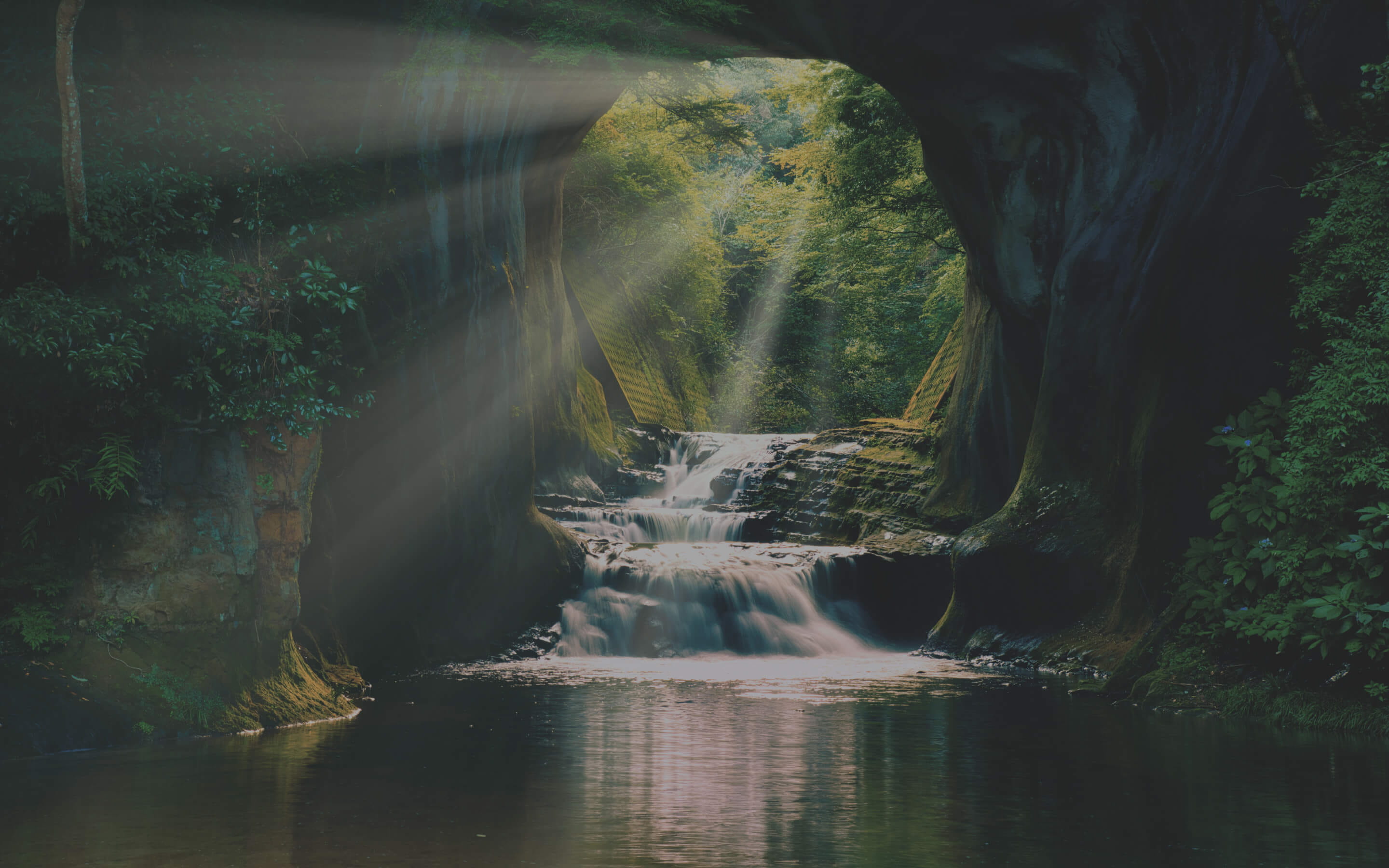 洞窟に差し込む光と奥に流れる小さな滝