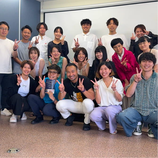 書籍を手にした人々が笑顔で集まっている集合写真